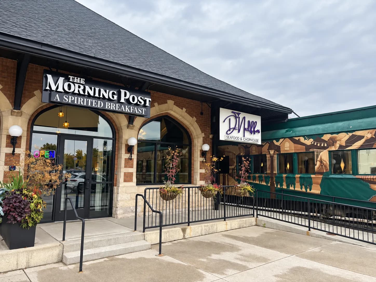 The Morning Post's sign above its Lansing entrance, with D'Nulffos Seafood & Chophouse's sign and the restaurant's vintage railcar mural next door